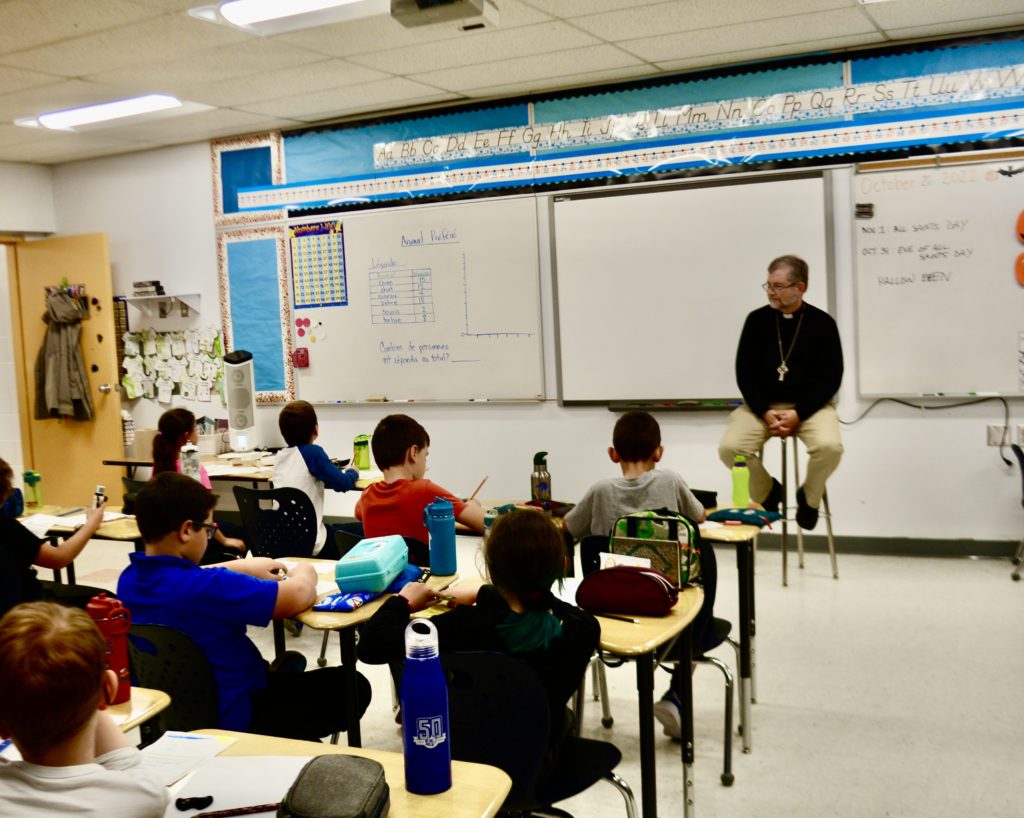 The Bishop talks in front of a class